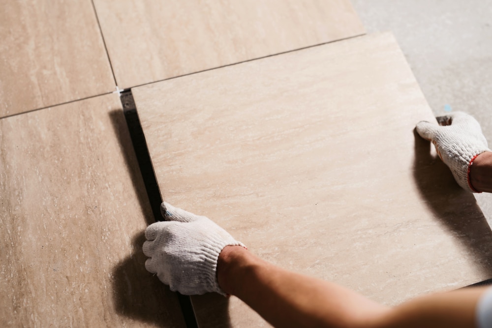 Person in gloves laying tiles before grouting