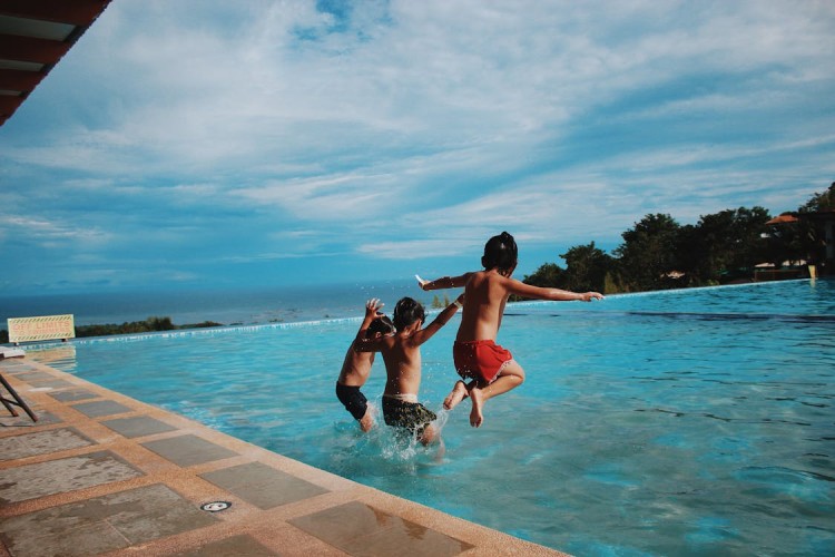 CHilderen jumping for swimming in a pavers pool